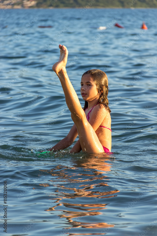 Девочка занимается гимнастикой в воде. Побережье Черногории, 2016