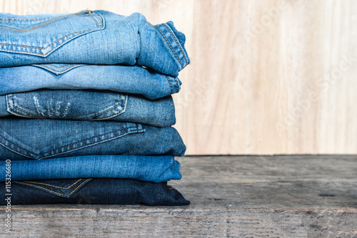 Jeans stacked on a wooden table unisex trendy fashion