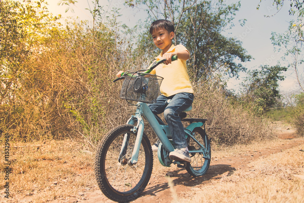 Fototapeta premium Little boy ride bicycle on the rock road.