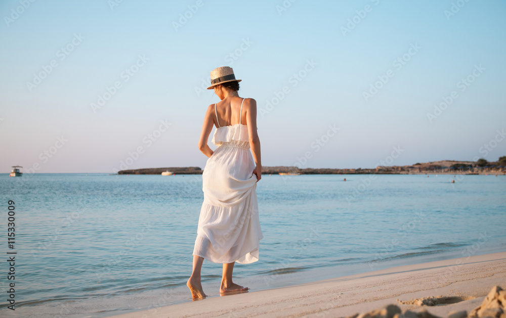 Happy woman in a white sundress walking by the beach Happy woman in a white sundress walking by the beach