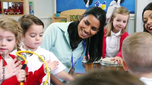 Nursery students enjoying a music lesson in the classroom with their teachers.