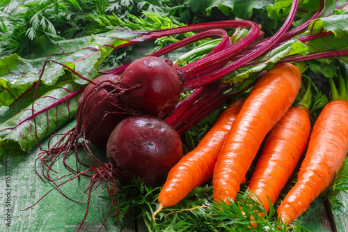A bunch of young organic carrots and beets with leaves on a wooden table. Vegetables from the garden