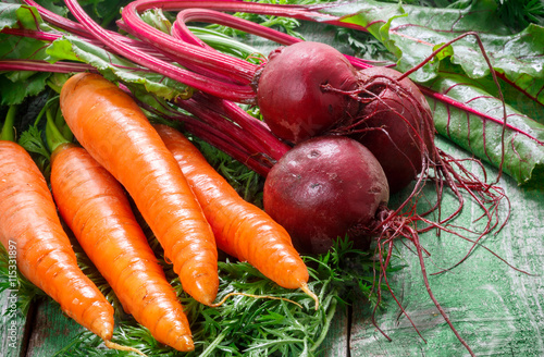 A bunch of young organic carrots and beets with leaves on a wooden table. Vegetables from the garden