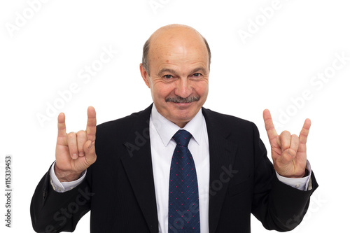 Elderly man in a suit shows a sign of the horns