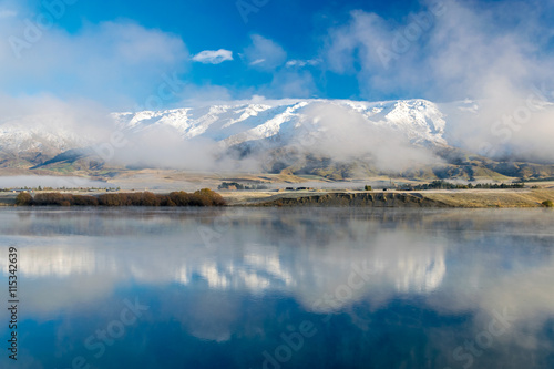 Winter morning view of Pisa range (part of the southern alps reflected in lake Dunstan, Cromwell, New Zealand