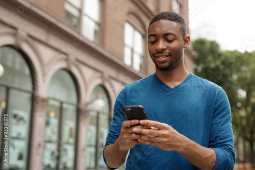 Young black African American man in city texting cell phone