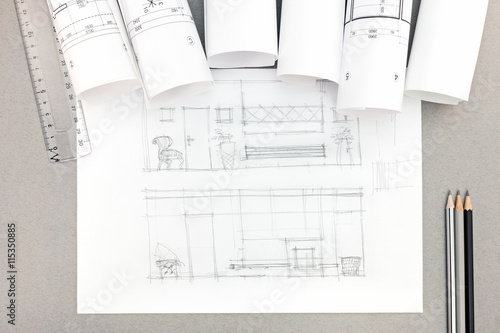 architectural hand-drawn sketch with blueprint rolls on desktop