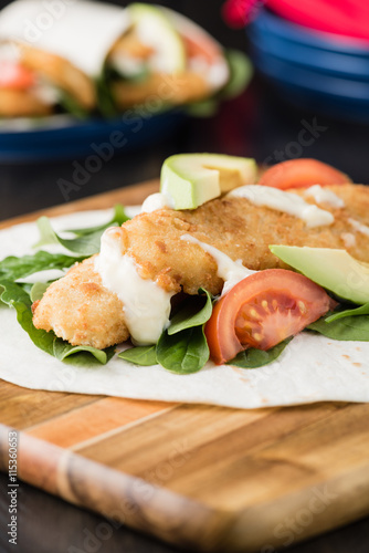 Crumbed fish fillet burrito with avocado and tomato