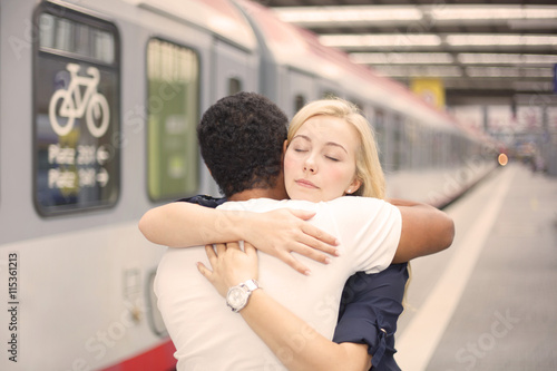Interracial couple hugging at the train station