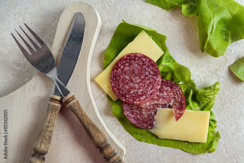 Breakfast with salami, cheese and salad on rustic background