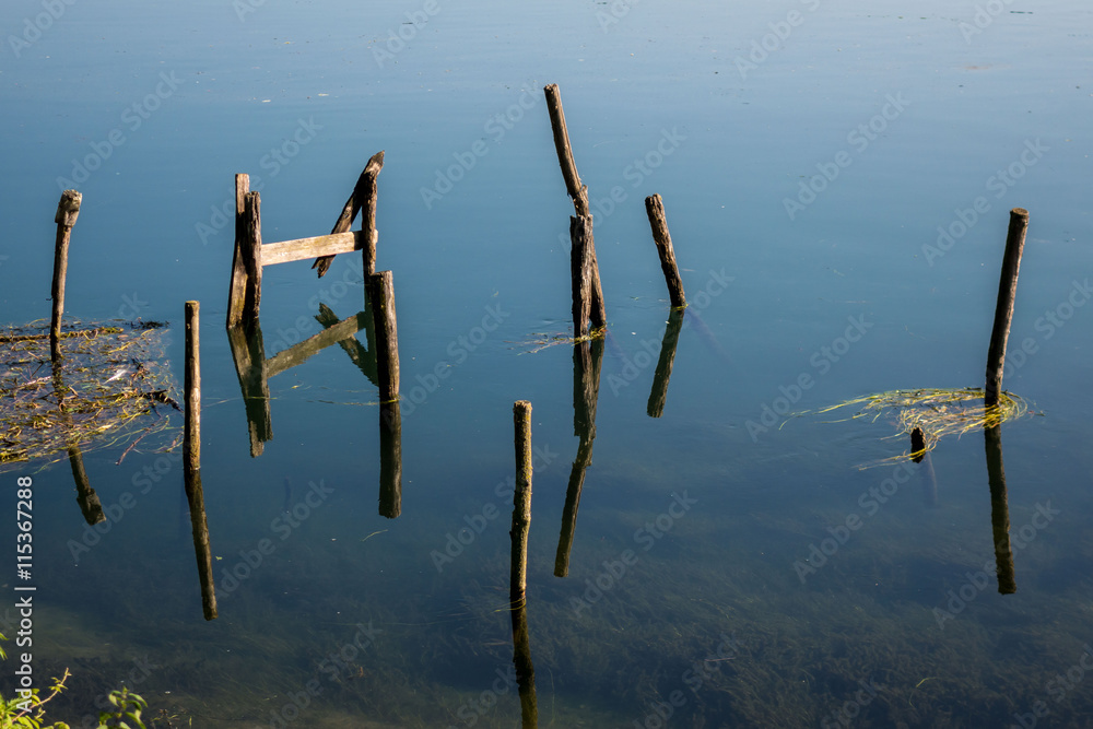 Pali di legno che emergono dalle acque azzurre di un fiume
