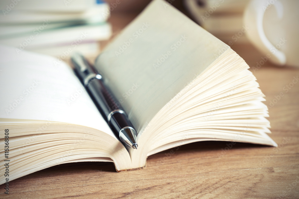 Open book with pen on wooden table Open book with pen on wooden table