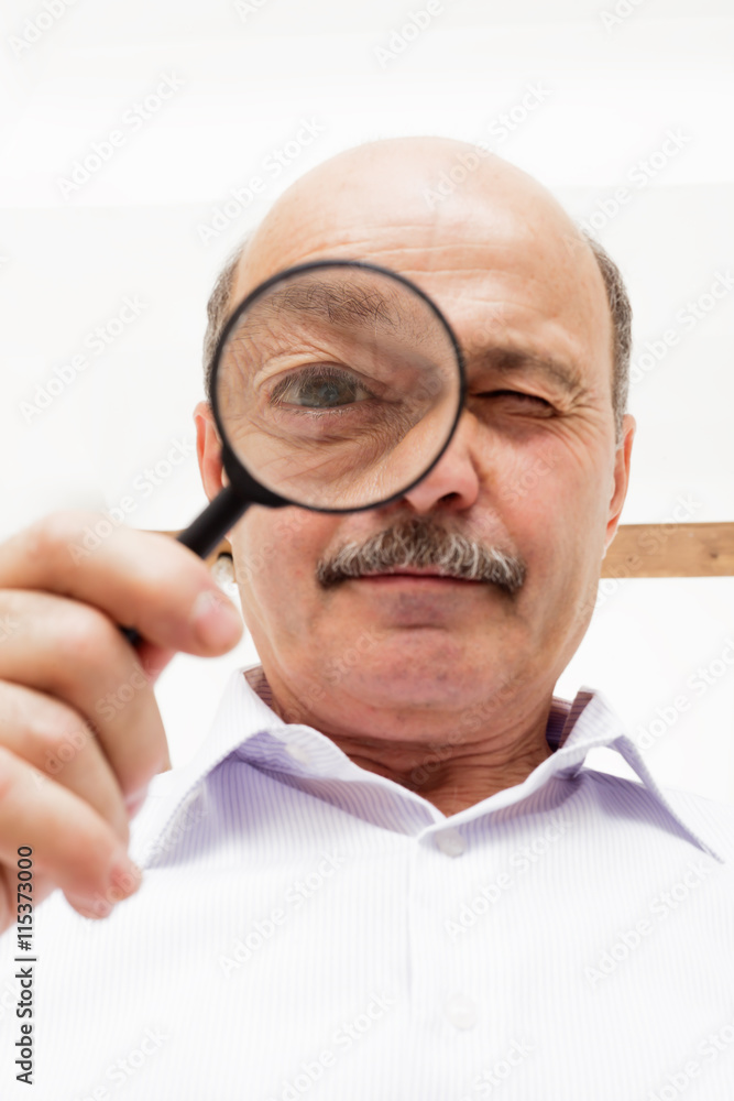 elderly man looks at something through a magnifying glass. elderly man looks at something through a magnifying glass.