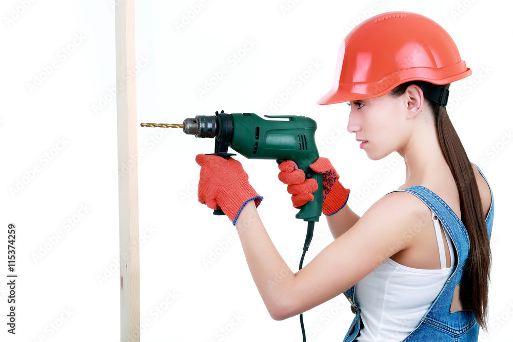 Portrait of young female builder in overalls and helmet with dri Portrait of young female builder in overalls and helmet with dri