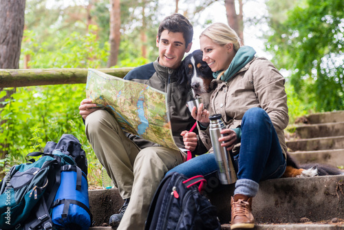 Mann und Frau beim Wandern im Wald planen die nächste Etappe auf der Karte photo