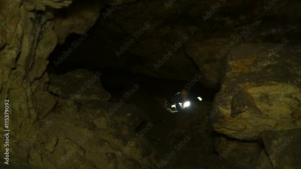 Underground researchers climb in an underground tunnel. Passage through a narrow slit. Underground researchers climb in an underground tunnel. Passage through a narrow slit.