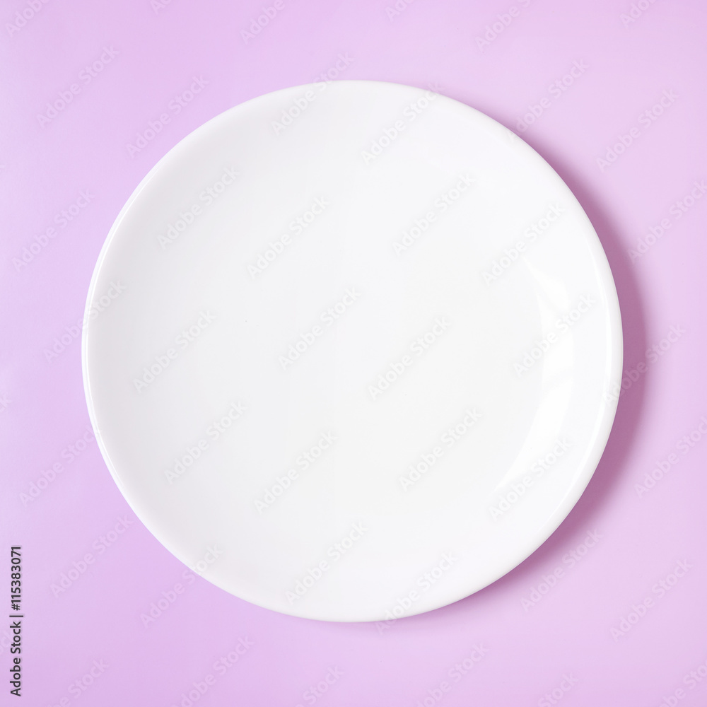 A plain white dinner plate on a pink background A plain white dinner plate on a pink background