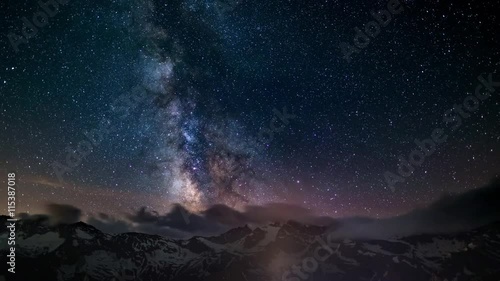 The apparent rotation of an outstandingly bright Milky Way and the starry sky beyond snowcapped mountain ridge, captured at high altitude in summertime on the Italian Alps. Time Lapse 4k video.
