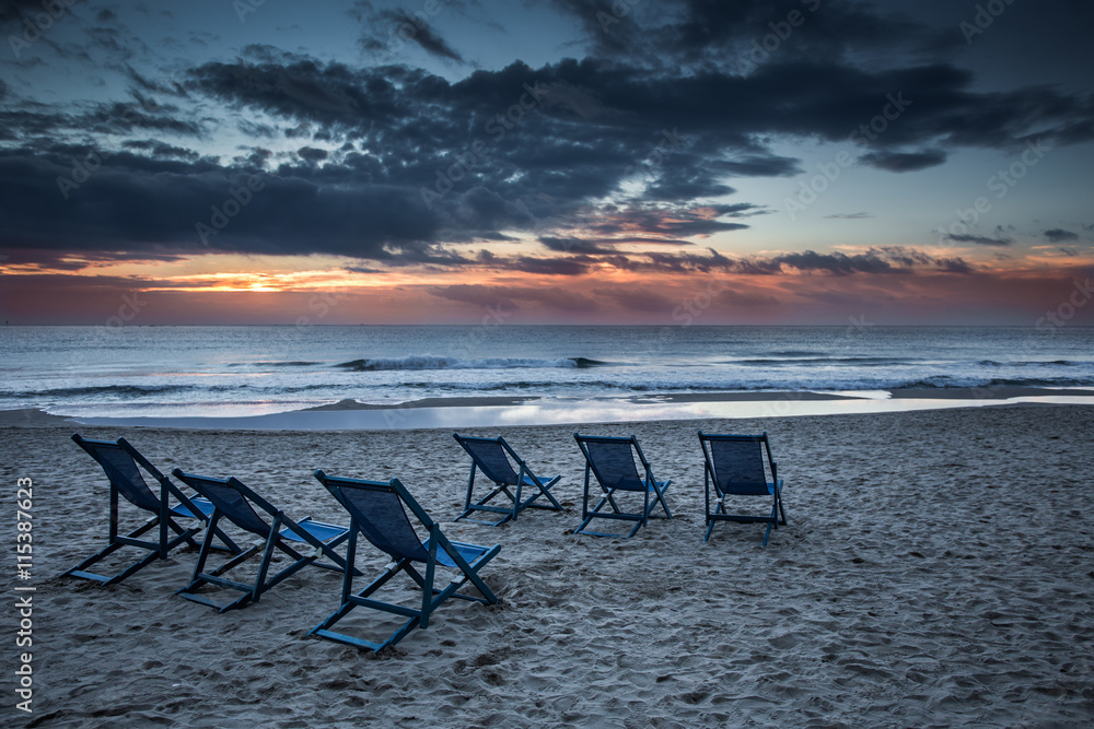 Six deckchairs on the beach with bright sun and waves Six deckchairs on the beach with bright sun and waves