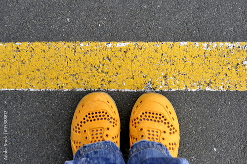 Top View of yellow shoes on the asphalt road with yellow line