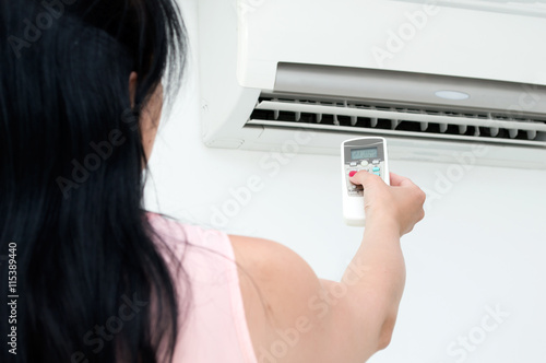 Woman turns on air conditioning in a room