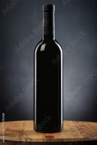 Bottle of wine on a wooden table on gray background