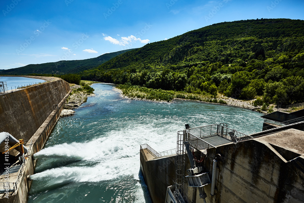 Dam of hydroelectric power plant in the mountains. Water rushing through gates at a dam. The dam closeup.