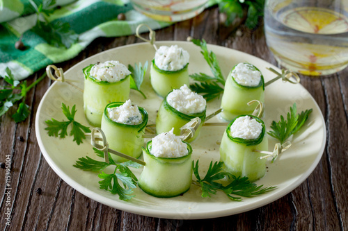 Cucumber rolls stuffed with feta cheese, dill and olives on a wo