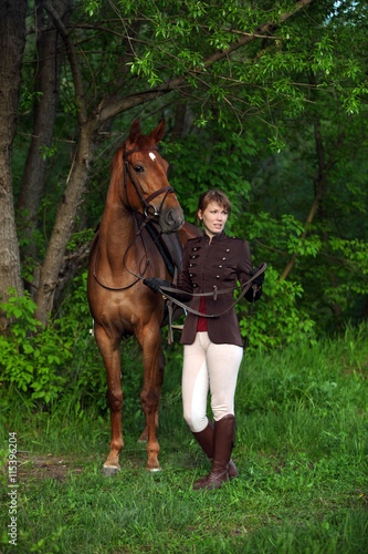 Beauty model girl in equestrian hunt uniform posing with horse