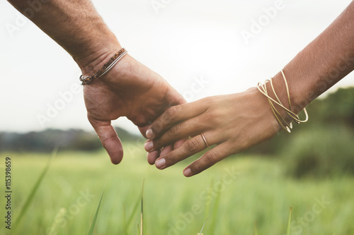 Fototapeta Loving couple holding hands in a field
