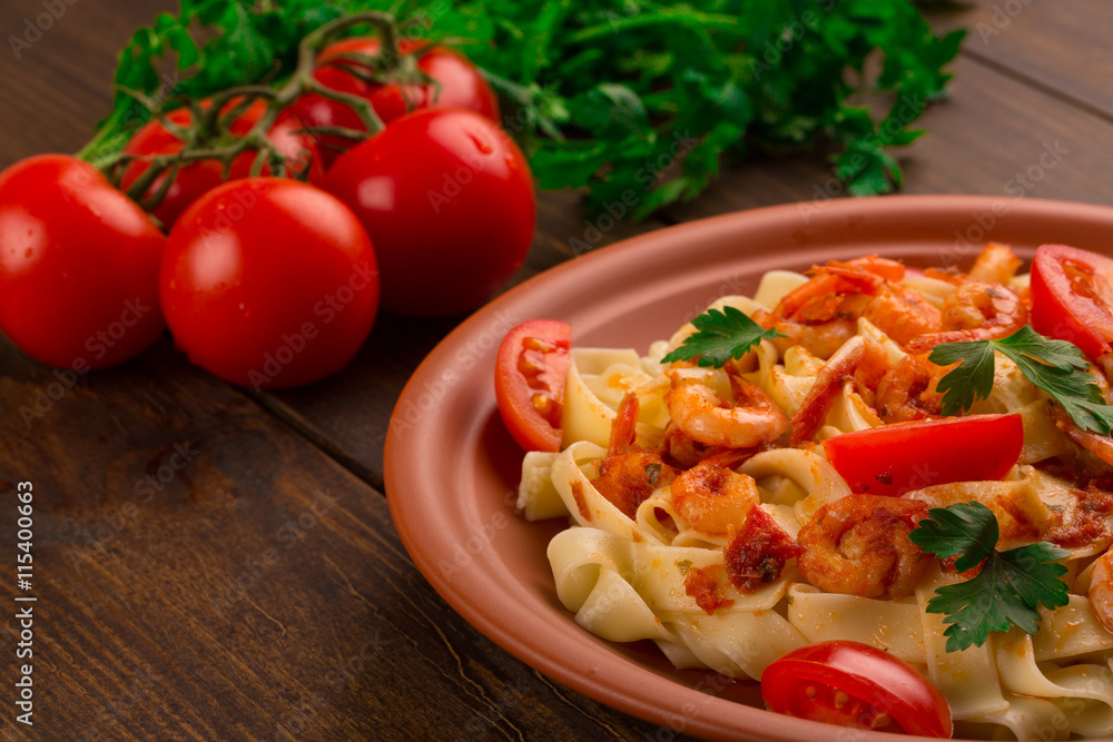 Fettuccine pasta with shrimp tomatoes and herbs. wooden background Fettuccine pasta with shrimp tomatoes and herbs. wooden background