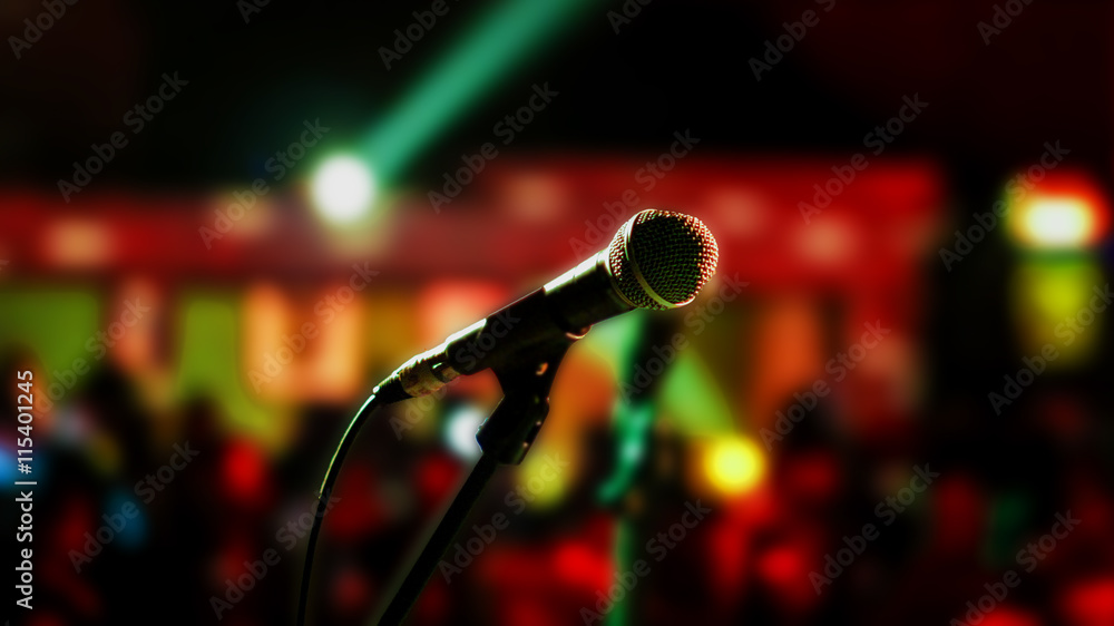 Microphone on stage ready for performer with full audience blurred background - obrazy, fototapety, plakaty 