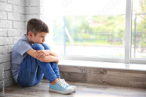 Sad boy sitting near window