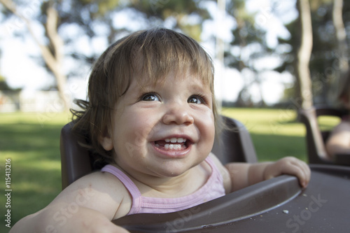 happy baby enjoying in park waiting in feeding chair for food