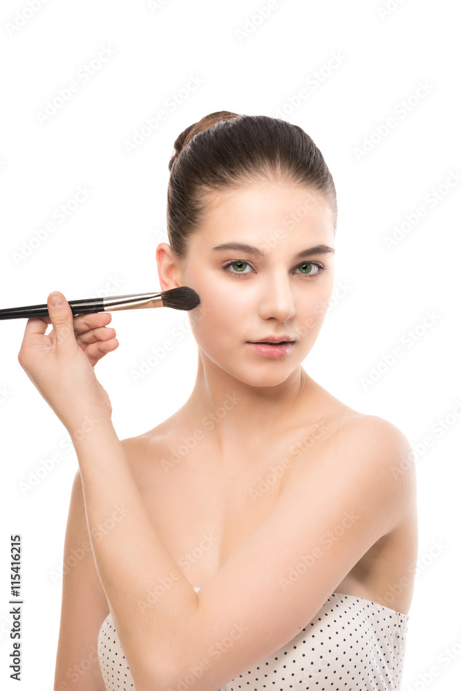 Fototapeta premium Portrait of beautiful young brunette woman with clean face. Beauty spa model girl with perfect fresh clean skin applying cosmetic brush. Youth and skin care concept. Isolated on a white background.