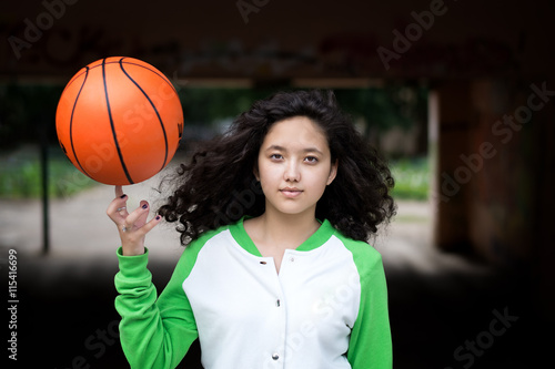 Portrait of a young brunette with a basketball in the street