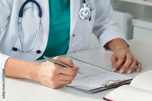 Female medicine doctors hands filling patient medical form