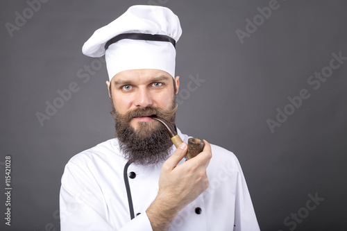 Closeup portrait of a bearded chef smoking a pipe photo