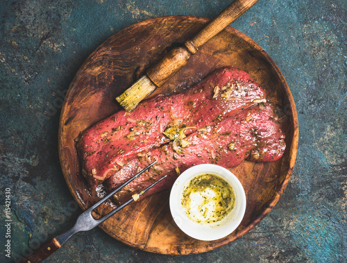Bilde på lerret Raw meat marinating on wooden plate with rub brush , top view