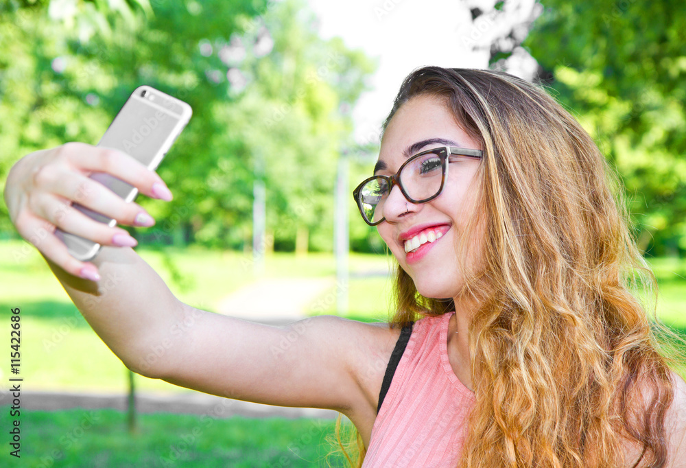 Outdoor portrait of beautiful girl taking a selfie with mobile p