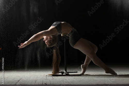 Fototapeta Naklejka Na Ścianę i Meble -  Woman doing gymnastic element on stand while sprinkled flour