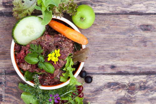 Fototapeta Naklejka Na Ścianę i Meble -  Futternapf, mit Barf- Frischfleisch mit Gemüse, Kräutern, Salat und Obst als Tabletop mit viel Textfreiraum