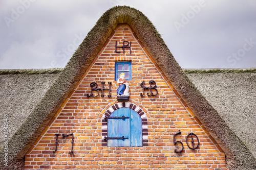 Friesengiebel Reetdachhaus mit Giebelschmuck und Eisenornamenten und Figur photo