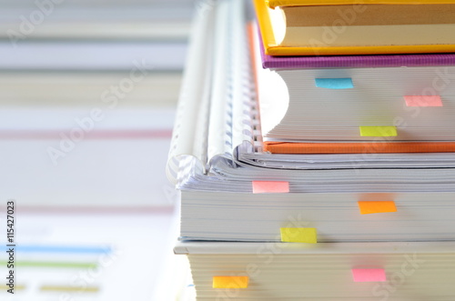 Pile of books and documents with paper notes on desk,high key tone.
