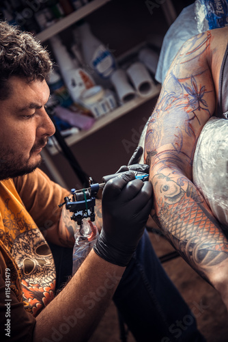 Tattoo specialist makes tattoo in tattoo parlor © Stop war in Ukraine!