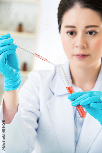 Young asian scientist pipetting in life science laboratory