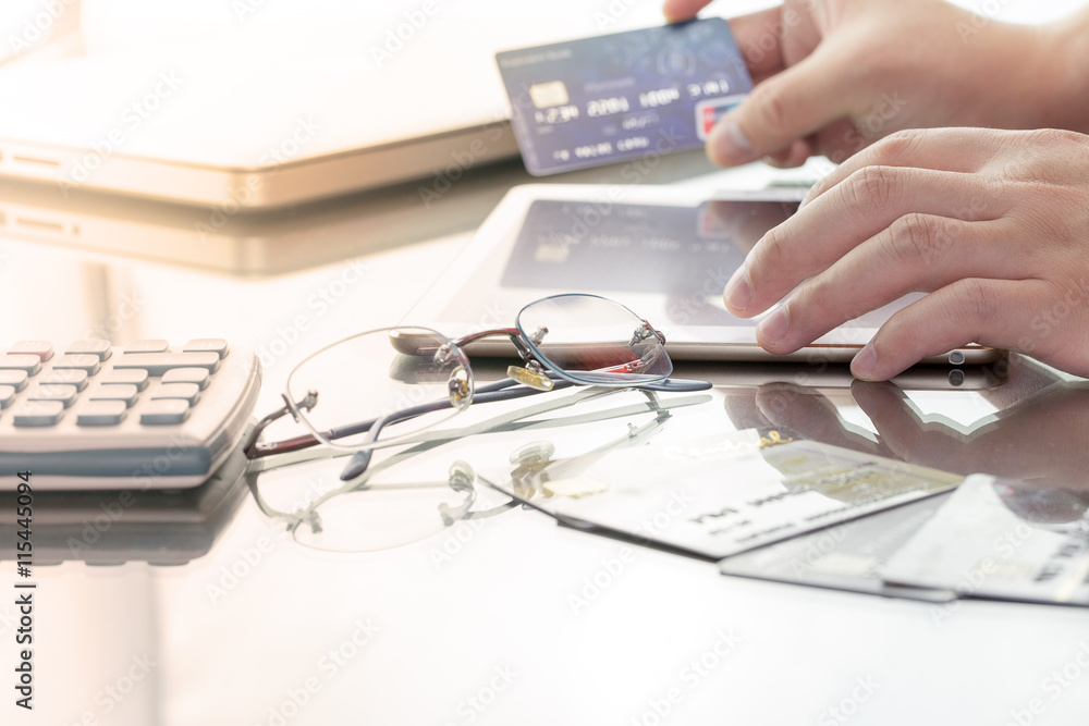 Man using his digital tablet while holding a credit card intent to online shopping, concept with digital business or e-commerce concept. close up, warm tone. Man using his digital tablet while holding a credit card intent to online shopping, concept with digital business or e-commerce concept. close up, warm tone.