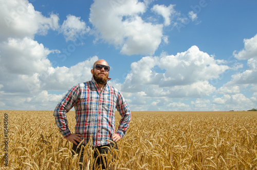 Happy smiling successful caucasian thirty years old farmer standing proud in front of his wheat fields © valerii kalantai
