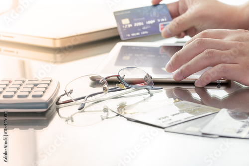 Man using his digital tablet while holding a credit card intent to online shopping, concept with digital business or e-commerce concept. close up, warm tone.