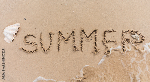 summer text background written on sand and piece of sea.